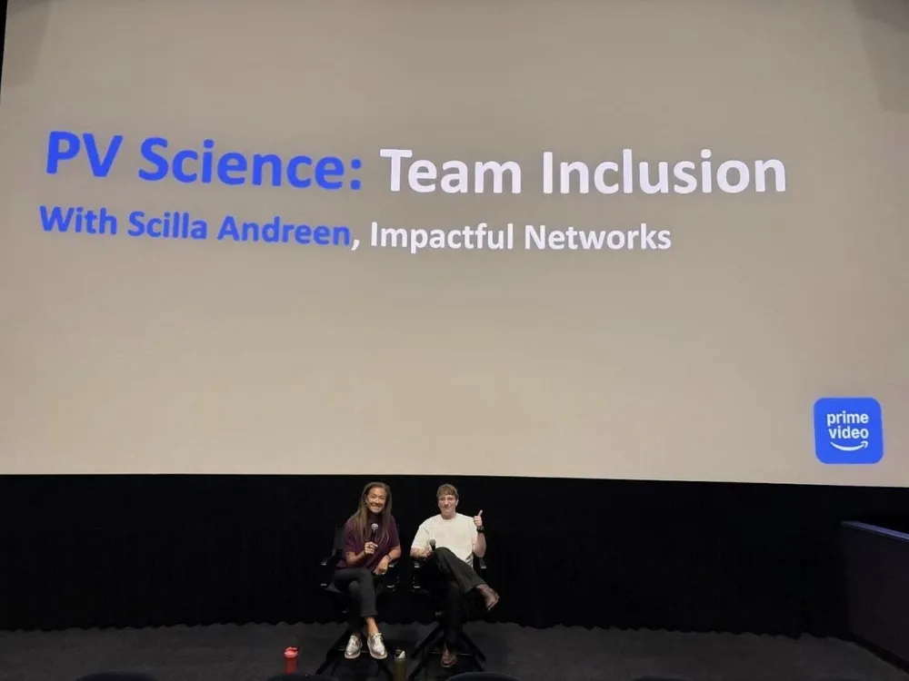 Two people in chairs beneath a cinema screen reading “PV Science: Team Inclusion, With Scilla Andreen, Impactful Networks” with a Prime Video logo.